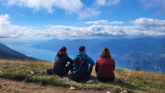 Gruppe junger Menschen sitzt auf einem Aussichtspunkt am Gardasee und genießt die Aussicht
